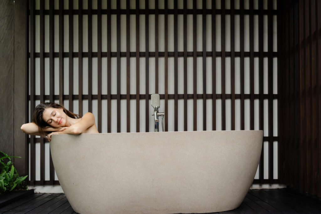 Woman relaxing in an outdoor stone bathtub at a Bali villa